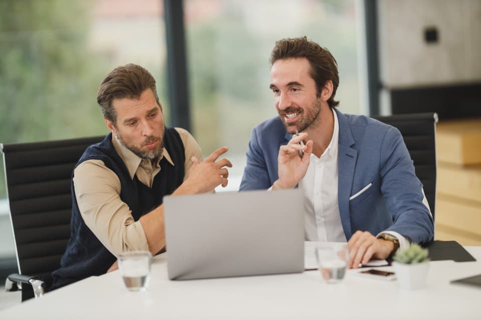 Duas pessoas discutindo números diante de um notebook